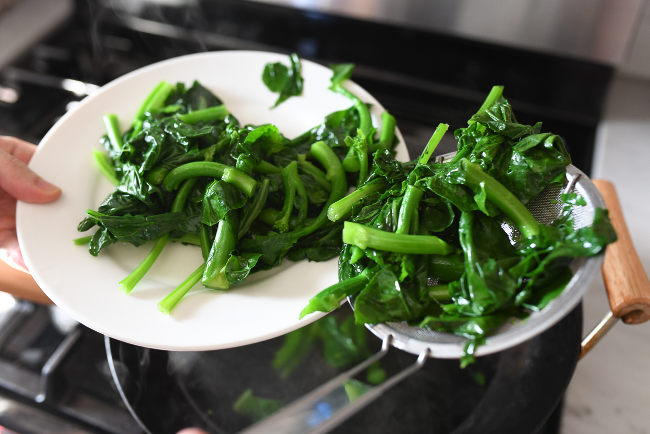 Removing blanched chinese broccoli from wok with strainer