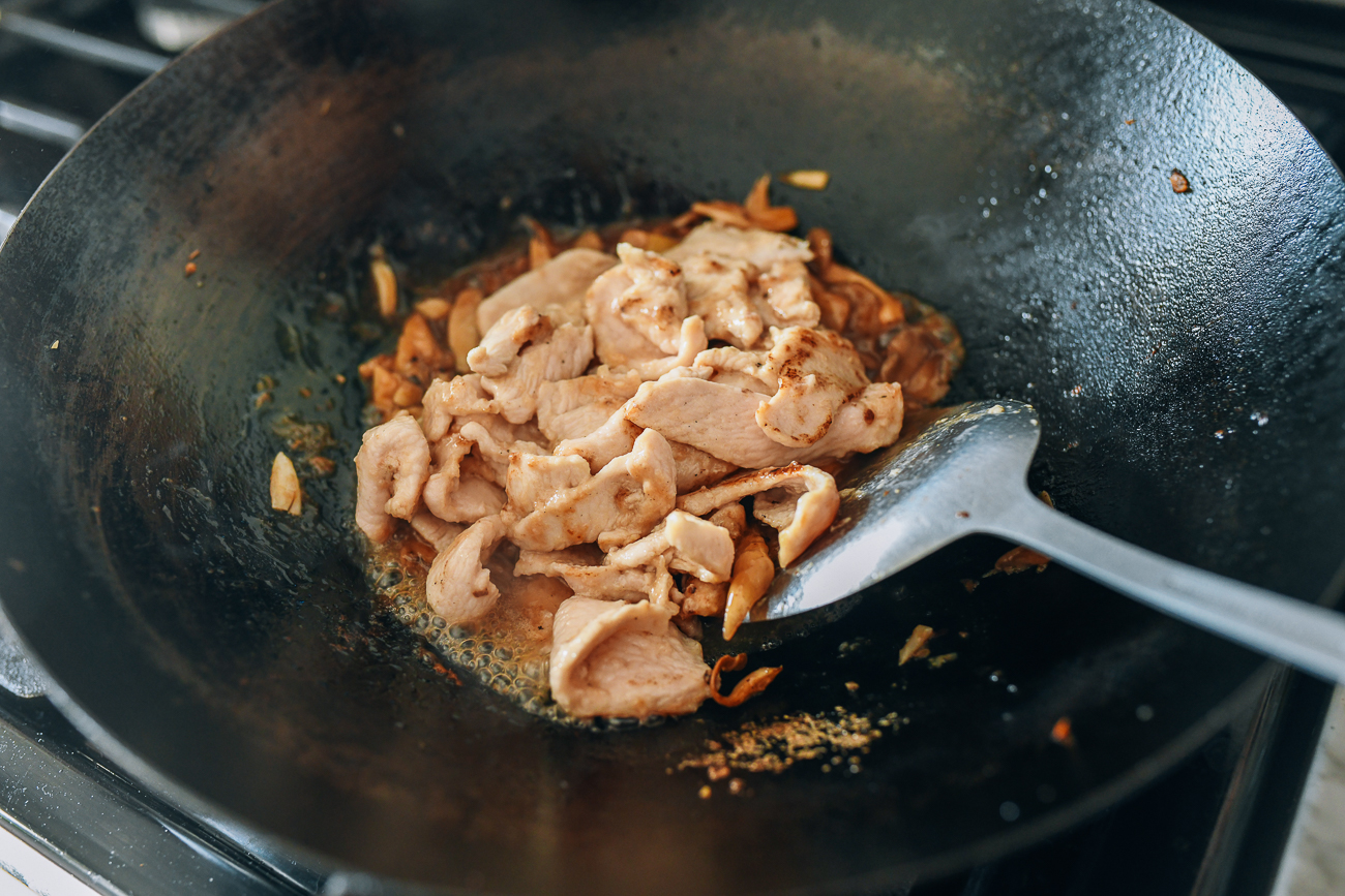 Adding sliced chicken to mushrooms and sauce