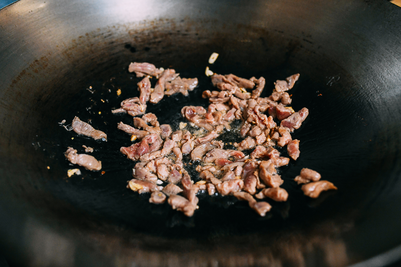 Stir-frying pork and garlic in wok