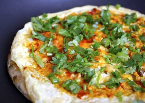 Frying pancake with egg and spicy bean sauce, cilantro, and scallion