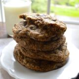 Pile of chocolate chip nut cookies with glass of milk