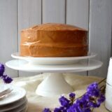 Peanut butter cake on cake stand with purple flowers