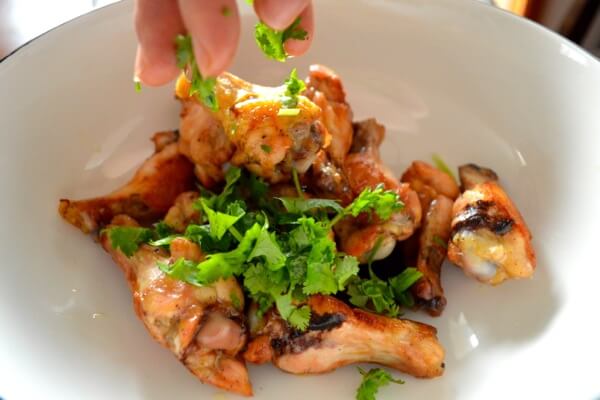 Sprinkling cilantro over sauced chicken wings