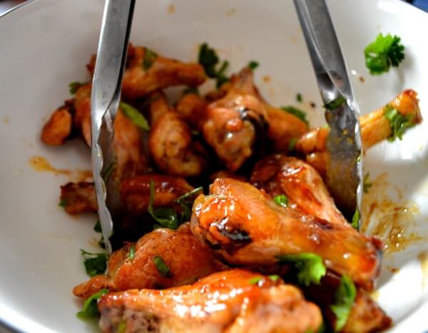 Tossing chicken wings with sauce and cilantro