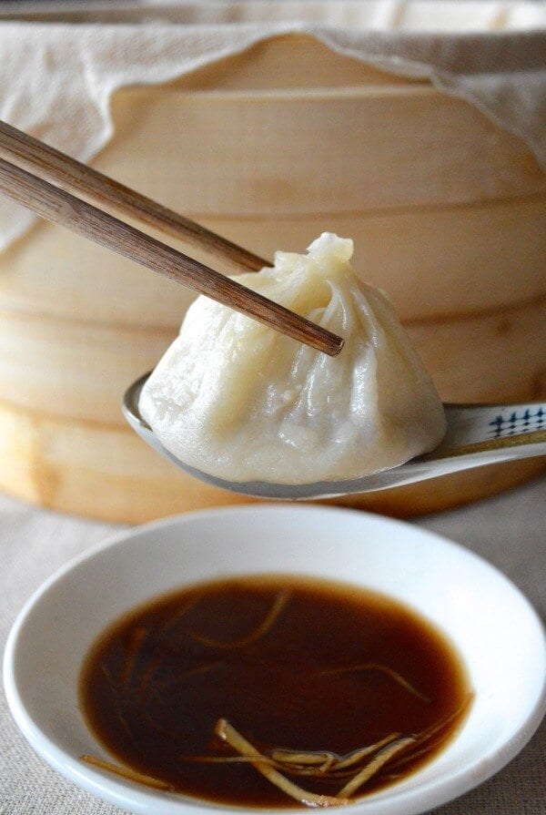 Dipping soup dumpling into black vinegar and ginger, by thewoksoflife.com