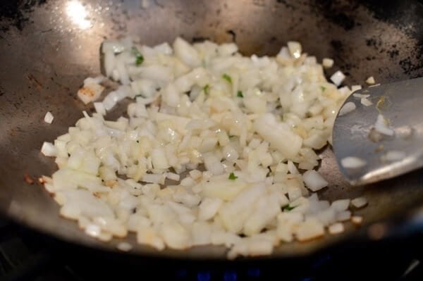 Stir-frying chopped onions in wok, thewoksoflife.com