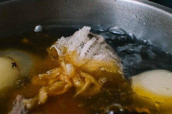 Aromatics tied in cheesecloth in broth, by thewoksoflife.com