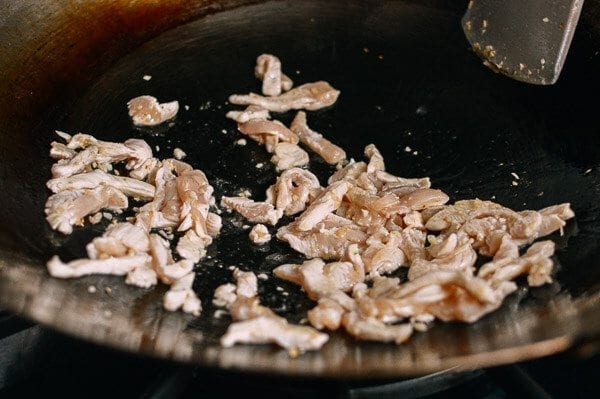 Stir-frying shredded chicken in wok, by thewoksoflife.com