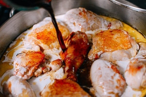 Adding soy sauce to Chicken Adobo, by thewoksoflife.com