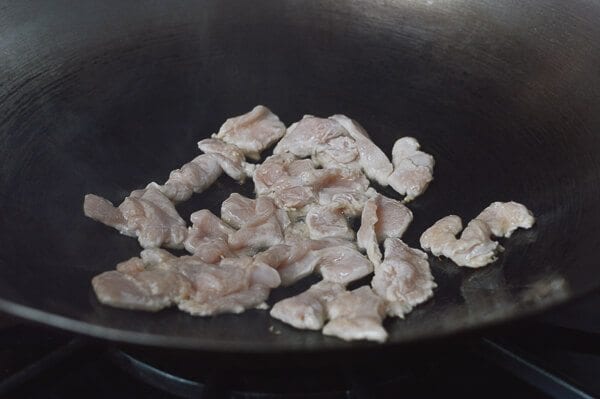 Searing chicken slices in a wok, by thewoksoflife.com