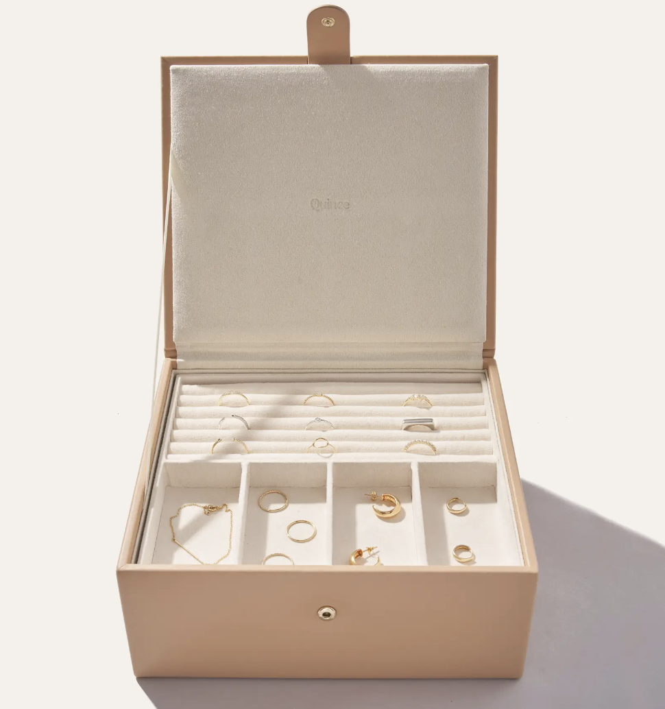 Beige jewelry case with gold jewelry sprinkled inside 