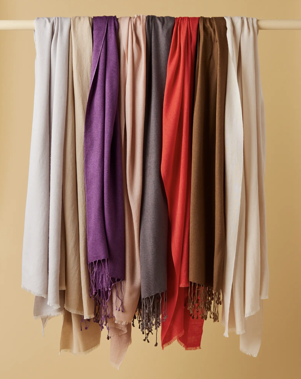 silk cashmere blend quince scarves of different colors arranged on a wooden peg