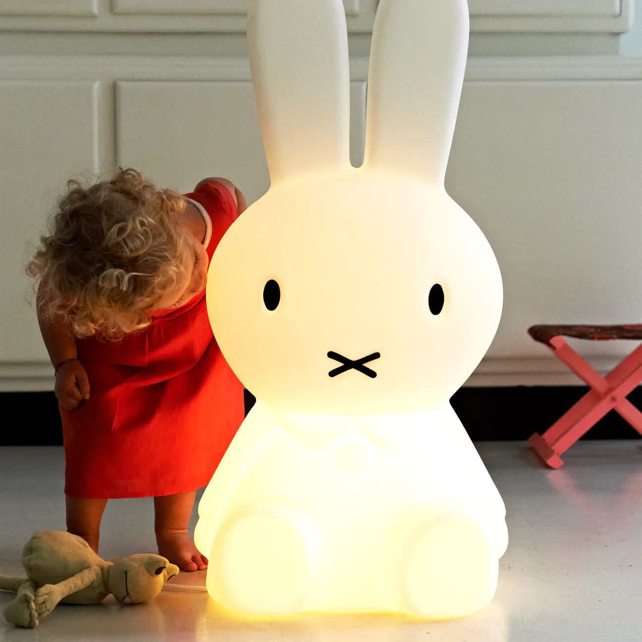 small child in red dress looking at Miffy XL floor lamp 