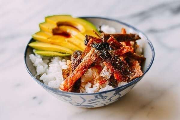 Salmon skin over top of rice with avocado slices. 