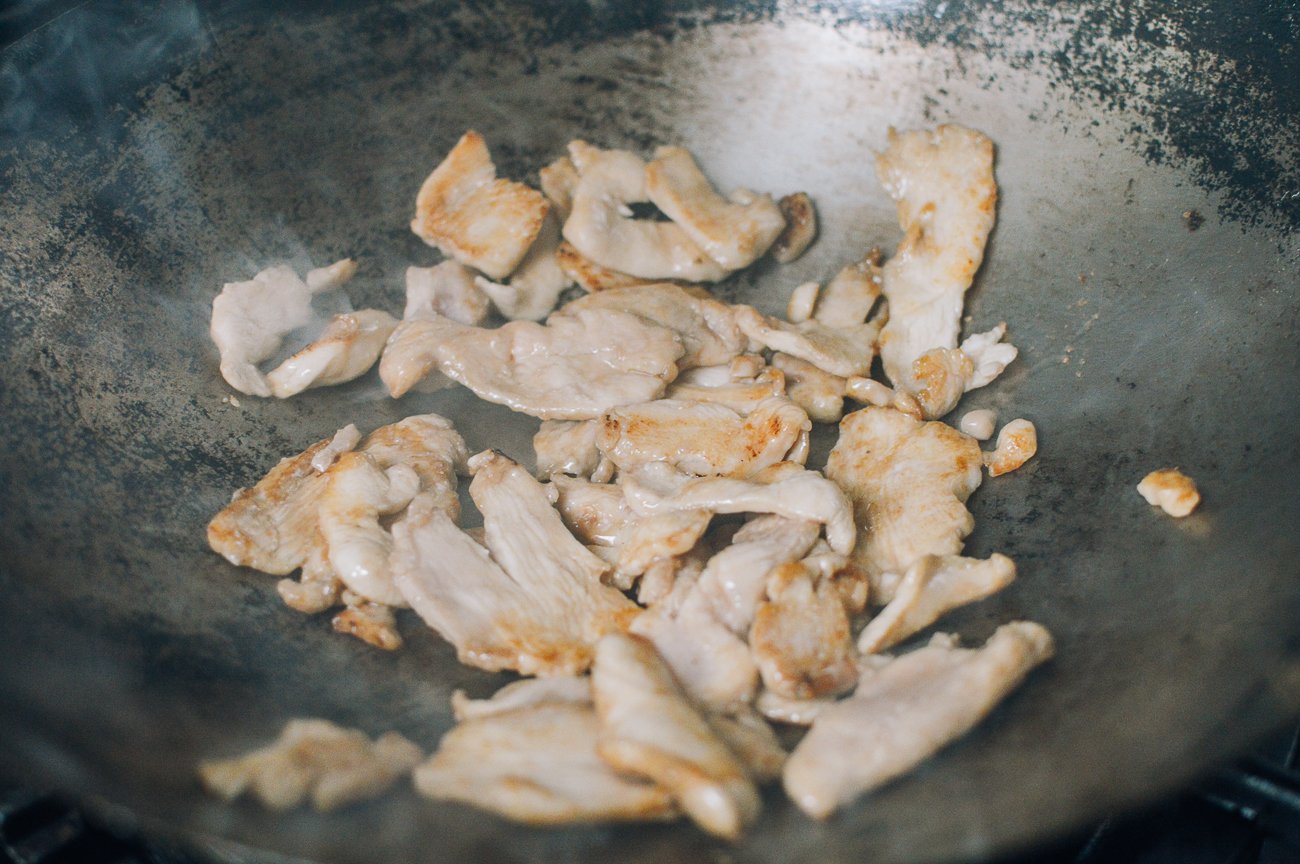 stir-frying chicken breast slices in wok