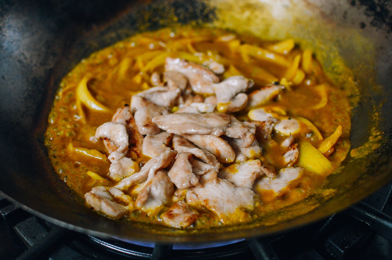 adding chicken to curry sauce with onions