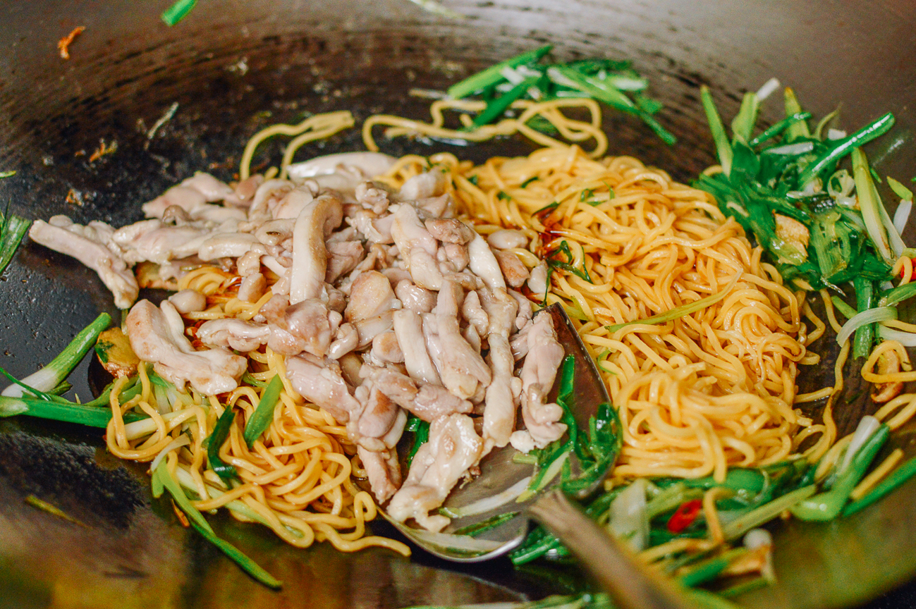 adding pre-cooked chicken back to wok with noodles