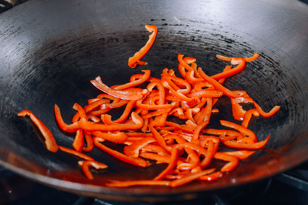 stir-frying red bell pepper slices in wok