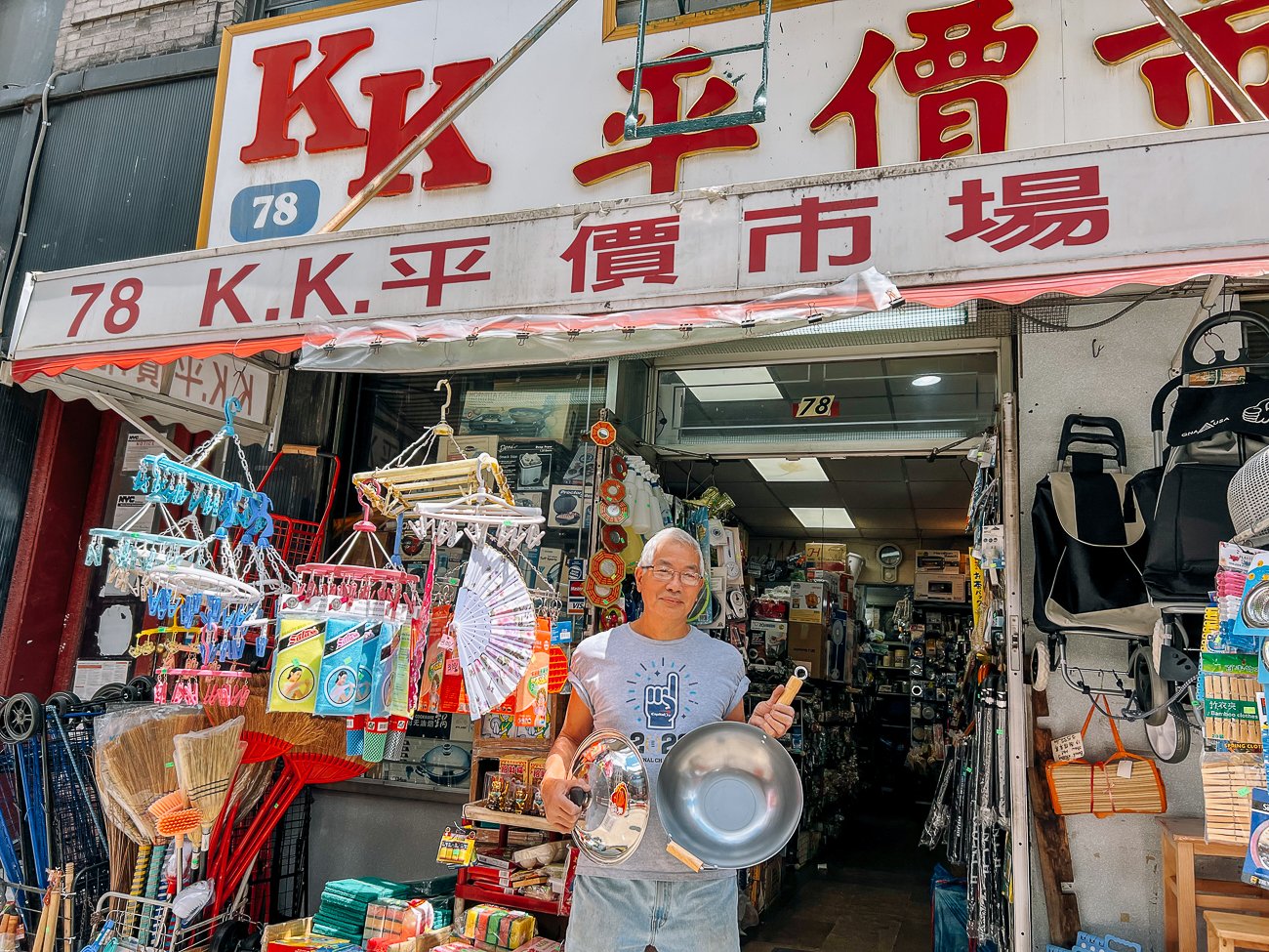 Mr. Li of K.K. Discount in Manhattan Chinatown holding a wok and lid