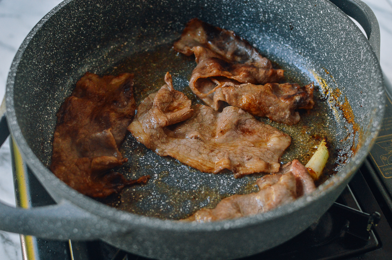 cooking thinly sliced beef in pan