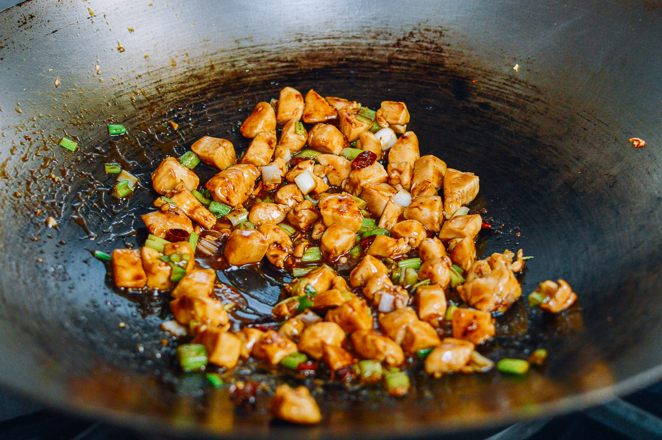 stir-frying kung pao chicken in wok