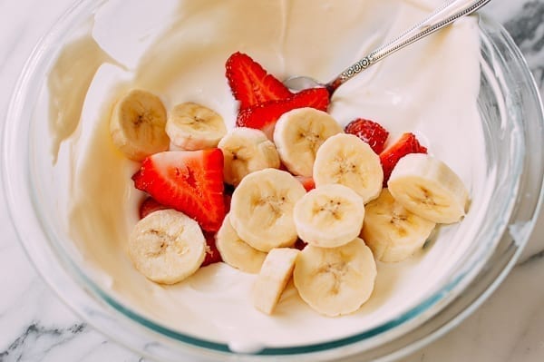 Folding sliced strawberries and bananas into yogurt mixture, thewoksoflife.com
