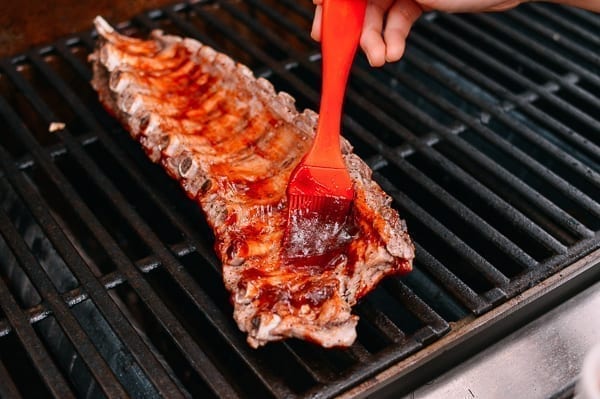 Brushing ribs with BBQ sauce on the grill, thewoksoflife.com