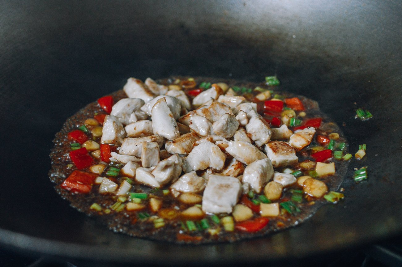 adding chicken to vegetables in wok
