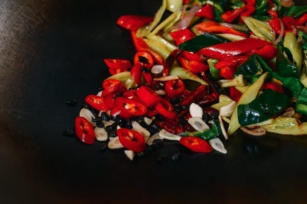 Adding garlic, black beans, and red chilies, thewoksoflife.com
