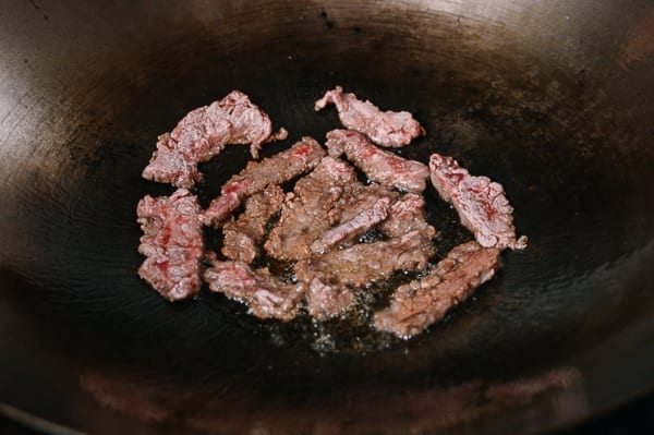 Frying dredged beef slices in wok, thewoksoflife.com