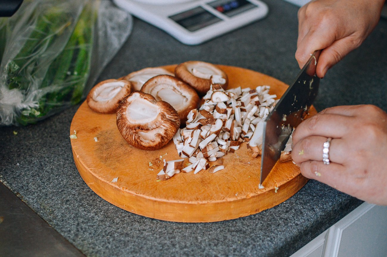 dicing fresh shiitake mushrooms on round cutting board