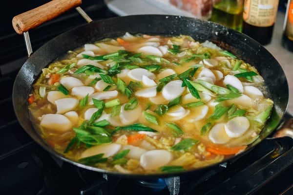 Adding rice cakes and scallions to the soup, thewoksoflife.com