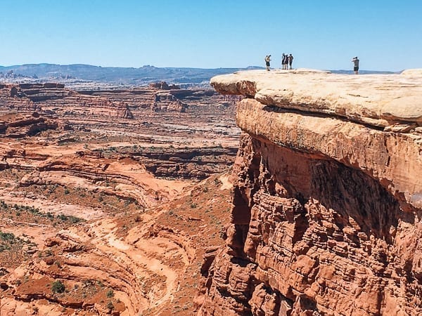 Hikers near white crack on White rim trail in Canyonlands by thewoksoflife.com