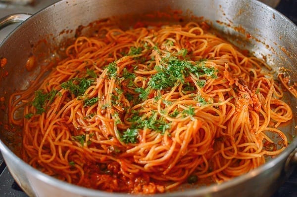 Garnishing tuna tomato pasta with fresh herbs, thewoksoflife.com