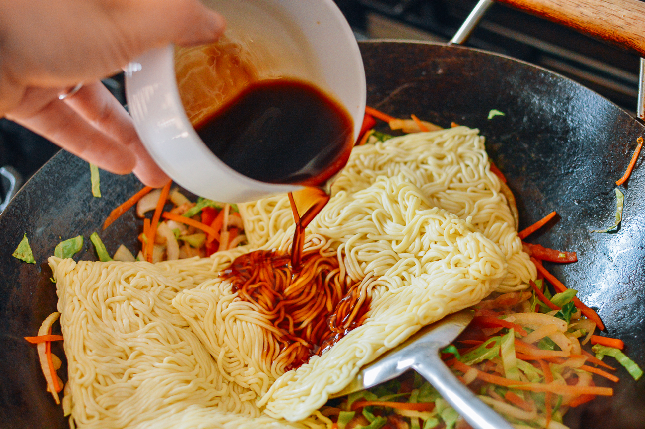 Pouring sauce over yakisoba noodles