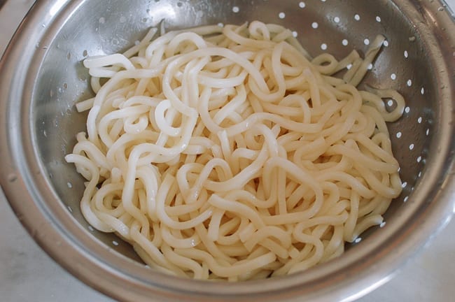 Drained udon noodles in colander, thewoksoflife.com