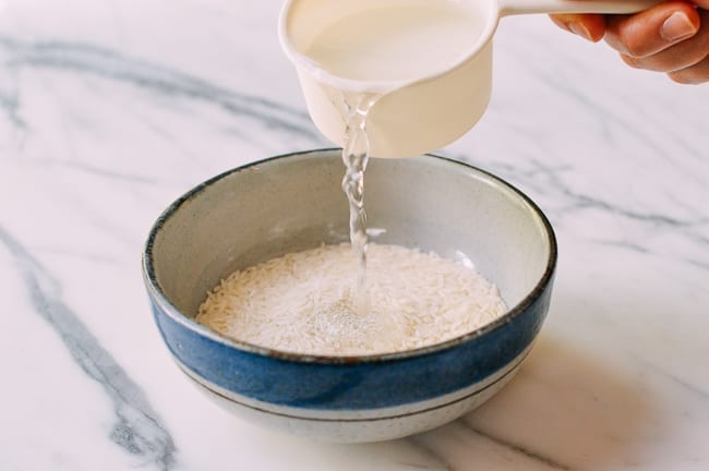 Adding water to rice in bowl, thewoksoflife.com