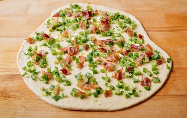 Dough sprinkled with bacon and scallions