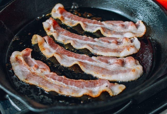 Cooking slices of bacon in cast iron pan
