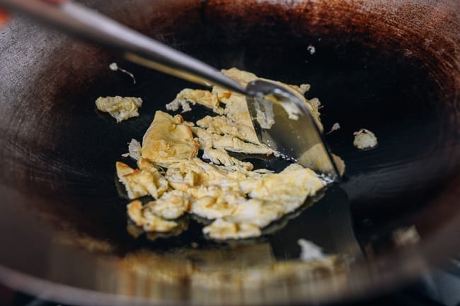 Breaking up scrambled eggs with wok spatula, thewoksoflife.com
