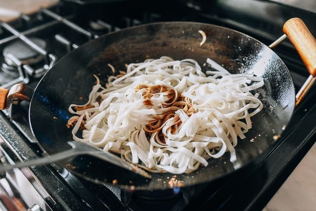 Adding noodles and pad Thai sauce to wok, thewoksoflife.com