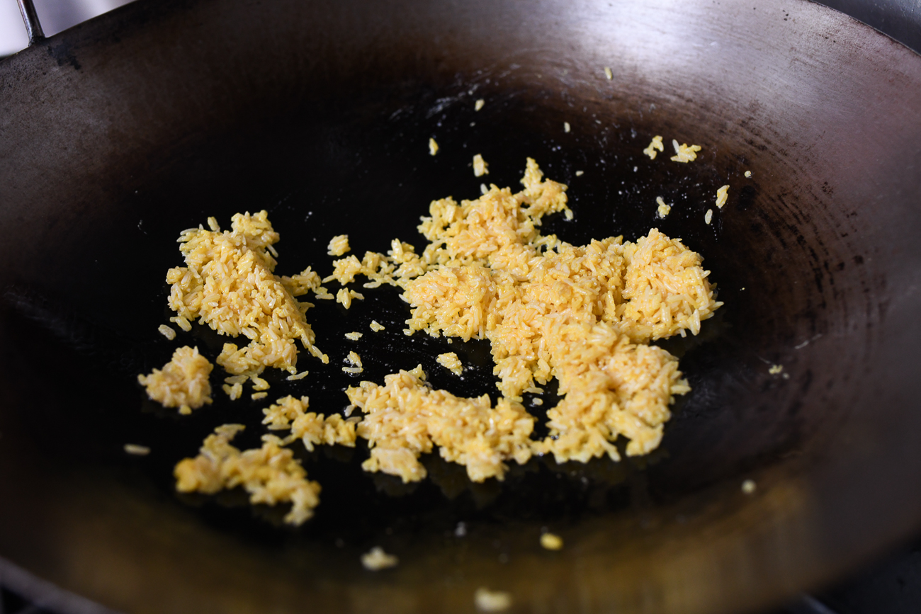 Stir-frying egg yolk coated rice in wok