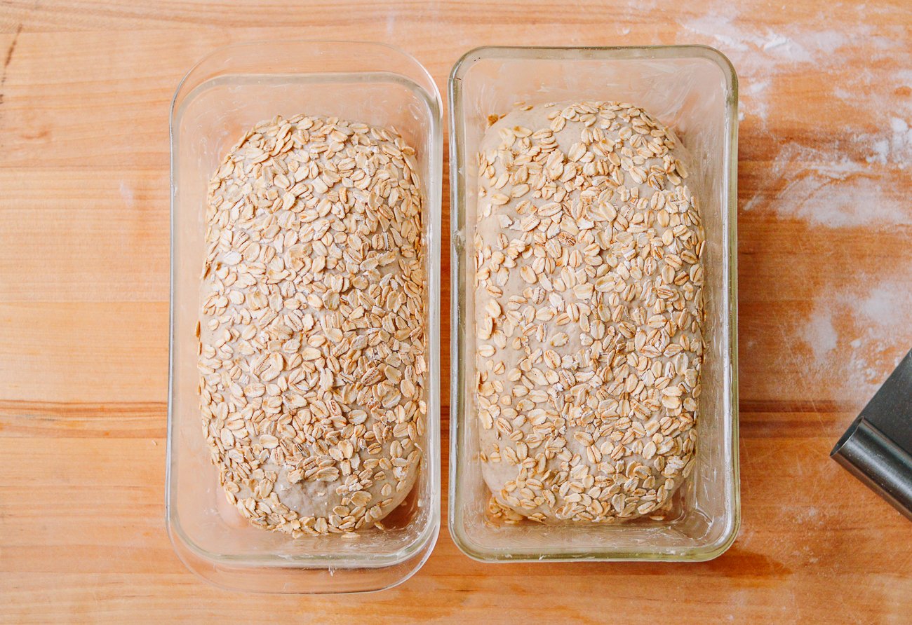 two loaves of multigrain bread in loaf pans before proofing and baking