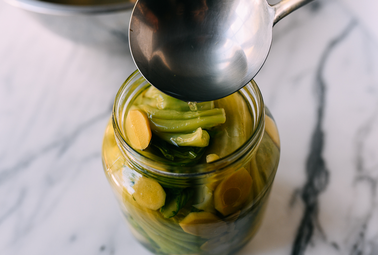 Filling jar of mustard greens with pickling liquid
