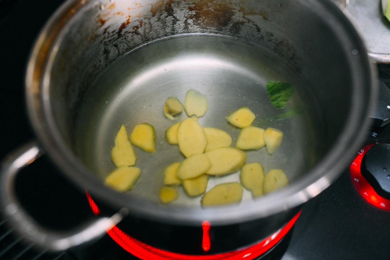 Adding ginger slices to water in pot