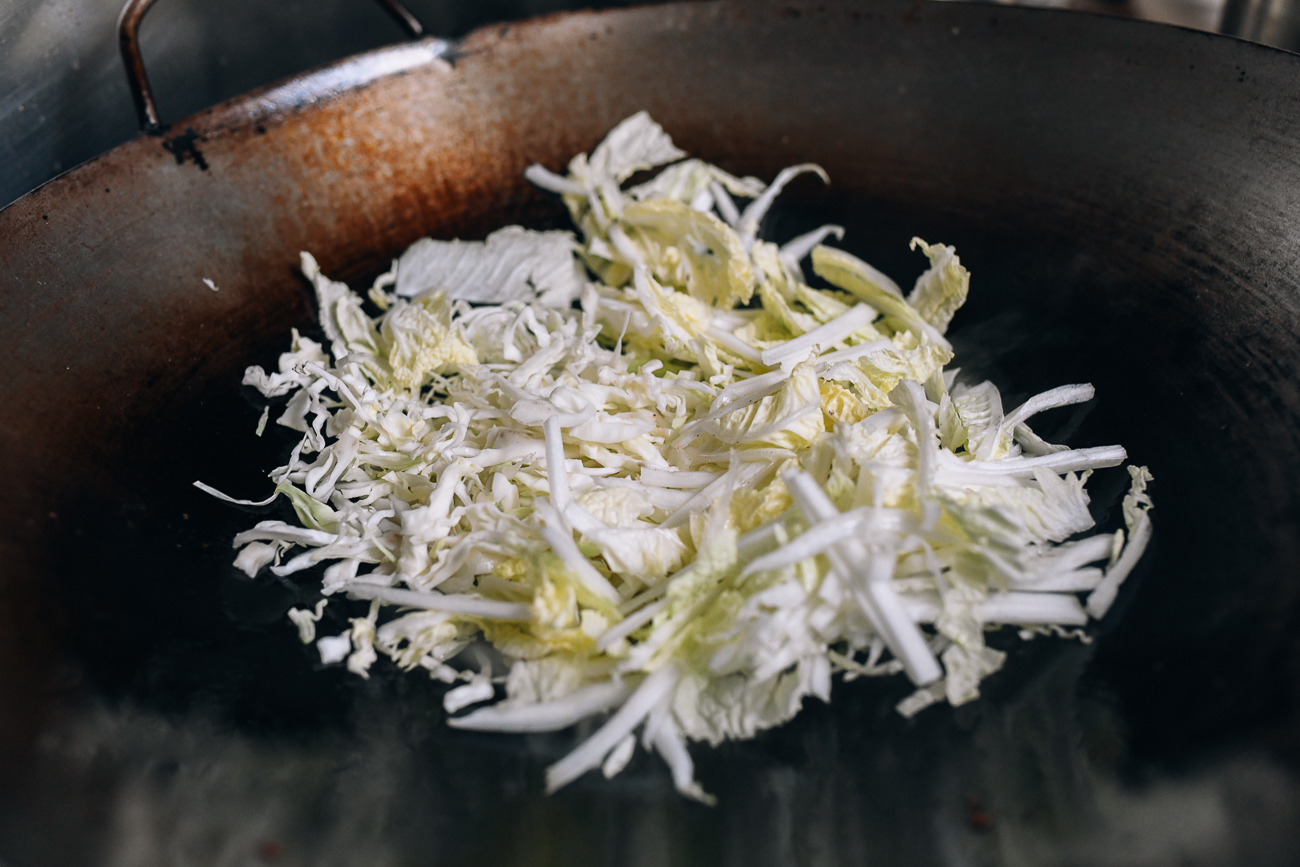 Adding shredded cabbage to wok