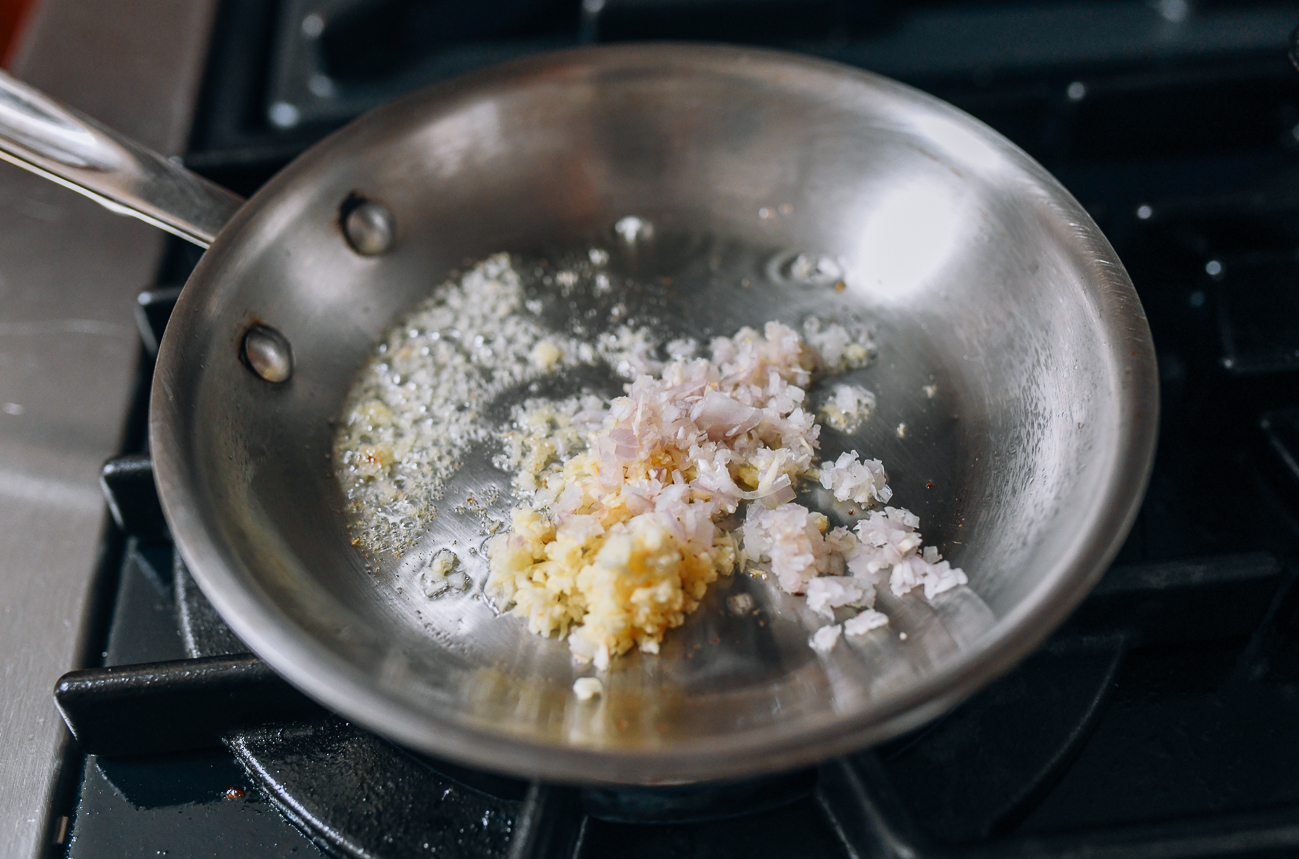 Adding garlic and shallots to pan with ginger