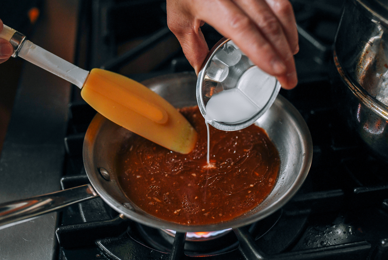 Stirring cornstarch slurry into sauce