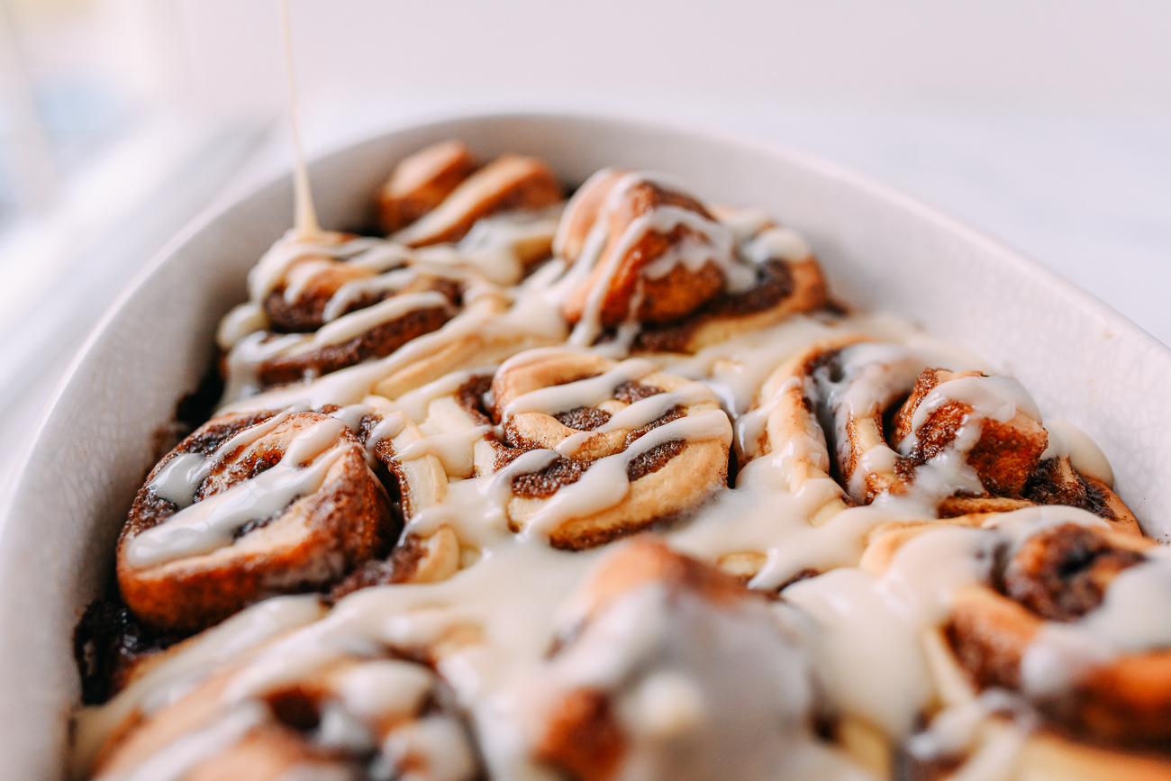 Pouring icing on fluffy cinnamon rolls