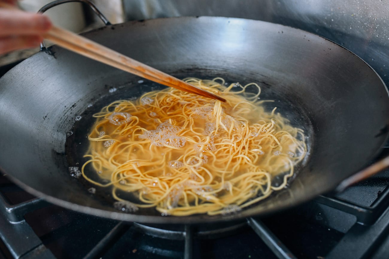 stirring lo mein noodles in boiling water to break them up